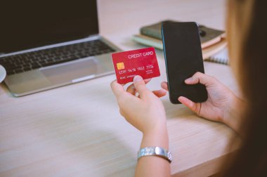 Kredi kartı tutan ve dizüstü bilgisayar kullanan genç bir kadın. Kafede çalışan bir iş kadını. Çevrimiçi alışveriş, e-ticaret, internet bankacılığı, harcama