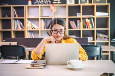 İş kadını internette bir kafede dizüstü bilgisayarla çalışıyor..