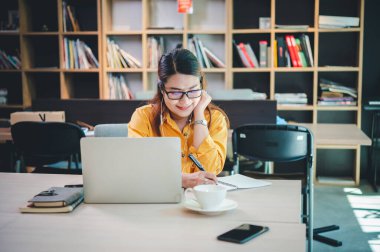 İş kadını internette bir kafede dizüstü bilgisayarla çalışıyor..