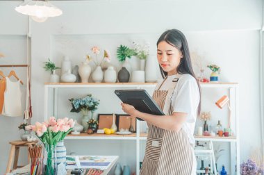 Küçük işletme sahipleri küçük bir dükkan hazırlıyorlar ve tableti kontrol edip siparişleri kontrol ediyorlar..