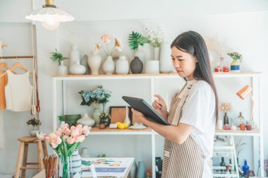 Küçük işletme sahipleri küçük bir dükkan hazırlıyorlar ve tableti kontrol edip siparişleri kontrol ediyorlar..