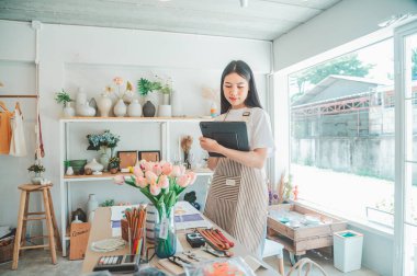 Küçük işletme sahipleri küçük bir dükkan hazırlıyorlar ve tableti kontrol edip siparişleri kontrol ediyorlar..