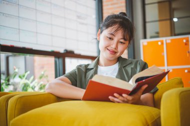 Bayan üniversite öğrencisi gün içinde bir kafede kitap okuyor..