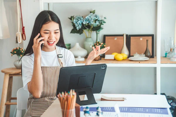 Small business owner talking on the phone with customers in a small shop. and check orders, check the orders that customers order from online retailers - online shopping