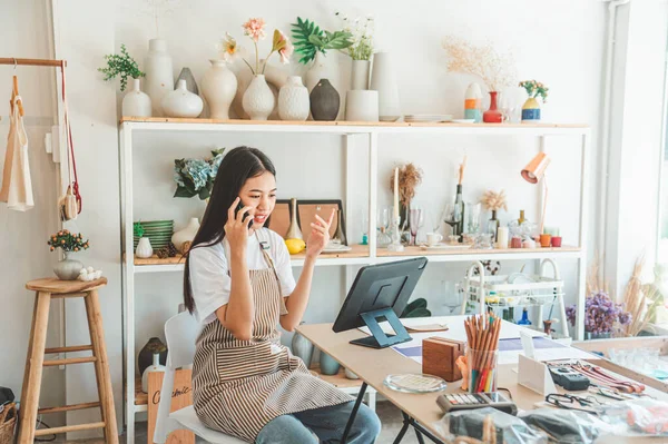 Small business owner talking on the phone with customers in a small shop. and check orders, check the orders that customers order from online retailers - online shopping