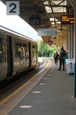 Cardiff, Wales - 20 Ağustos 2021: Galler 'de koruyucu yüz maskeleri hala zorunludur ve Queen Street Cardiff istasyonundaki yolcuların çoğu seyahat ederken yüzlerinin kapalı olduğundan emin olur.