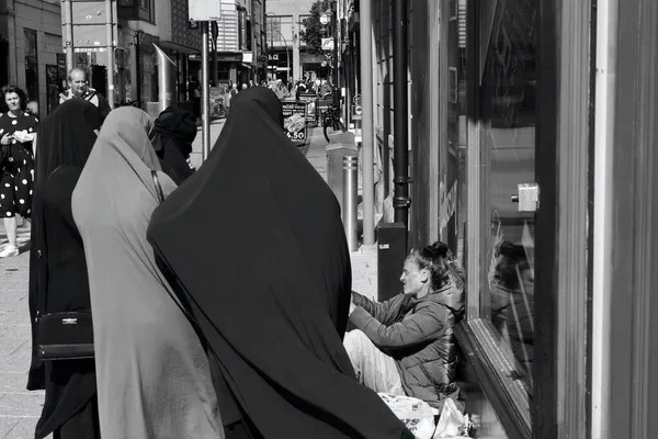 2021年7月31日 カーディフ市内中心部の舗装に座っている若いホームレスの女性 ヒジャーブのアジア系女性のグループが少女と話をするのを止める — ストック写真