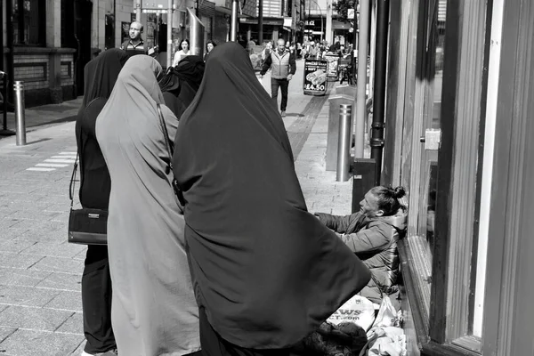 2021年7月31日 カーディフ市内中心部の舗装に座っている若いホームレスの女性 ヒジャーブのアジア系女性のグループが少女と話をするのを止める — ストック写真