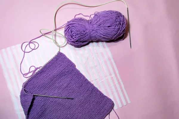 Çok Peri ipliği rengi ve pembe arka plan. Örgü süveter. Hobi ve eğlence konsepti.