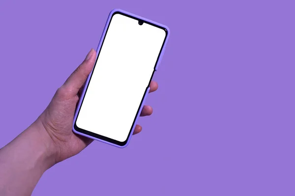 Female hand with a smartphone, mock-up on a lilac background,vertical position of the smartphone