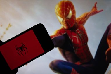 Rheinbach, Almanya 15 Ekim 2021, Örümcek Adam logosu TV 'deki Örümcek Adam filminden bir sahnenin önündeki akıllı telefonun ekranında (Örümcek Adam logosuna odaklan)