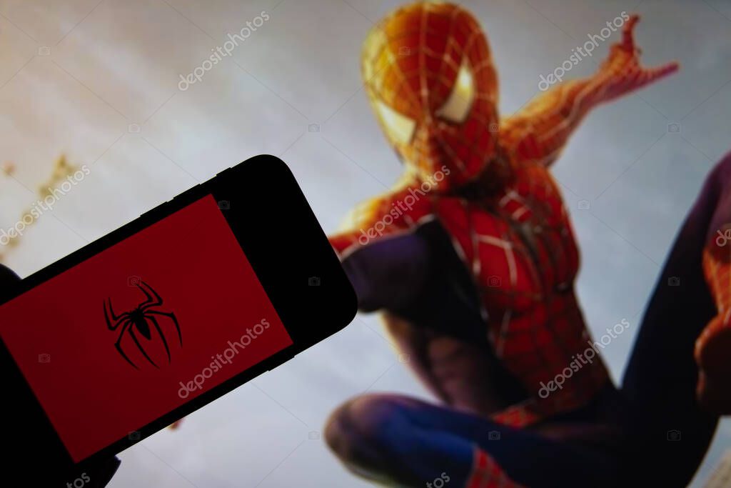 Rheinbach, Germany 15 October 2021,  The Spiderman logo on the display of a smartphone in front of a scene from a Spiderman film on TV (focus on Spiderman logo)