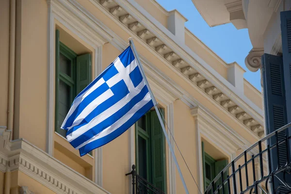 The Greek flag hangs from a balcony