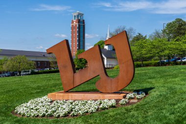 Lynchburg, Virginia - April 22, 2022: Large metal logo for Liberty University with the Freedom tower in the background . Freedom tower is part of the John W. Rawlings School of Divinity. clipart