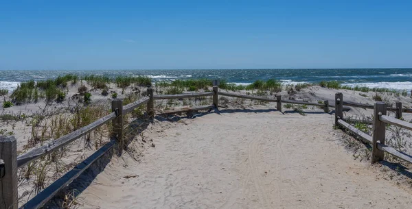 Atlantic Ocean beach background with path over the dunes and split rail fence
