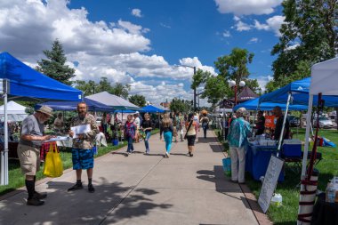Colorado Springs, CO - 6 Temmuz 2022: İnsanlar alışveriş yapıyor ve bir adam şehir merkezindeki Pioneer Müzesi 'nin bahçesindeki Colorado Çiftlik ve Sanat Pazarı' nda imza topluyor..
