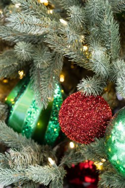 background of a red sparkly ball on an artificial Christmas tree with soft focus green balls and white lights