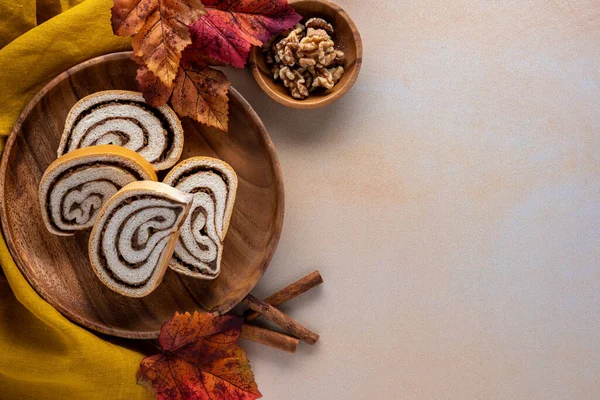 感恩节或秋季甜点背景 在有落叶和核桃的木制盘子上有切片坚果卷 — 图库照片