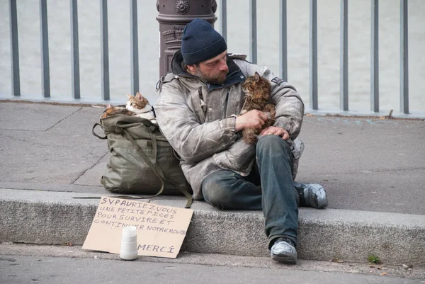 Paris, Fransa - 20 Nisan 2008: Evsiz adam ve kedileri Pont Saint-Louis kaldırımında oturmuş bir levhayla lütfen hayatta kalmak ve yolculuğumuza devam etmek için biraz bozukluk isteyin