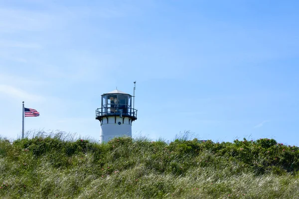 チャタム灯台と米国の旗の上には ビーチから見た風に草やピンクのバラで覆われた崖を見上げ — ストック写真