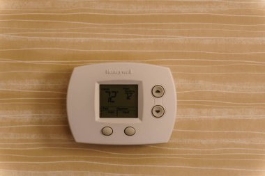 Easton, MD - 5 Nisan 2019: Honeywell termostatı sarı ve beyaz duvar kağıtlarıyla bir duvara monte edildi.