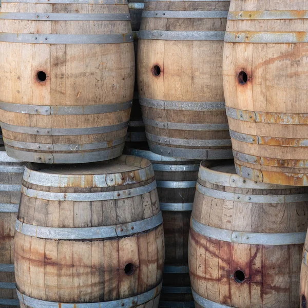 stack of multiple oak barrels used for aging wine with stains from red wine in square aspect ratio