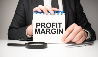 Adam gümüş bir kalem ve el ele tutuşma kartı ile bir not defterine yazar. Gri arka plan, ön manzara. işletme ve eğitim kavramı.