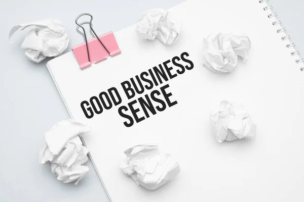 GOOD BUSINESS SENSE. Blank sheet of paper, red paper clip, word Ideas and crumpled paper wads