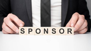 Tahta bloğu tutan bir iş adamı. İş adamı SpONSOR 'la tahta küpleri izliyor. Finansal. finansman