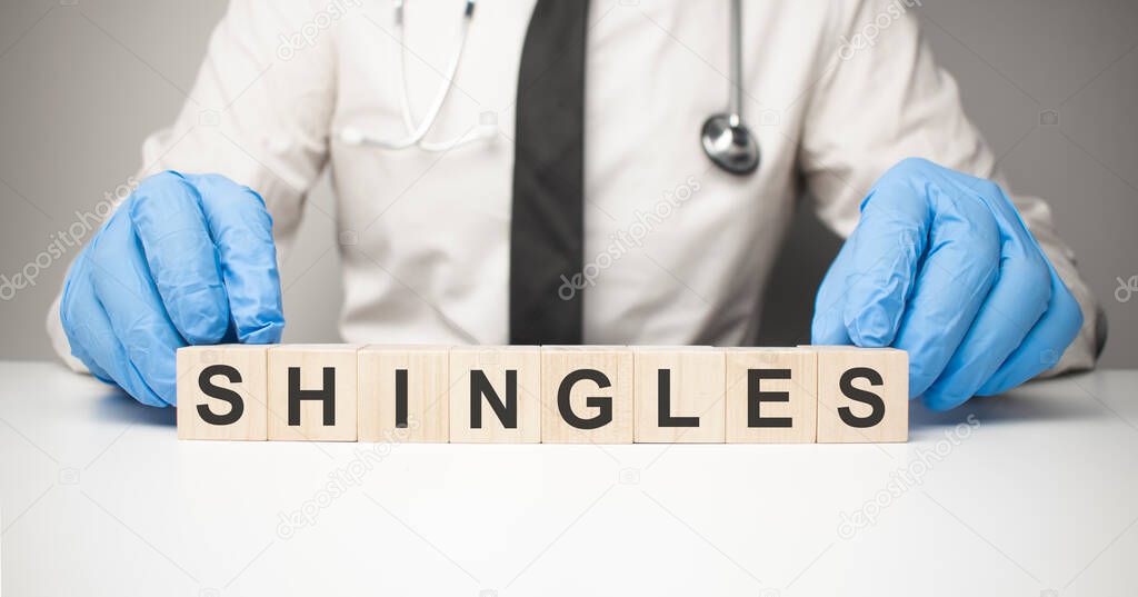 Doctor holds wooden cubes in his hands with text shingles