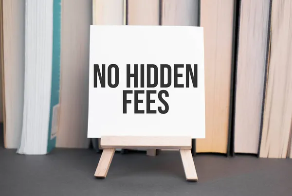 White card with text NO HIDDEN FEES stands on the desk against the background of books stacked