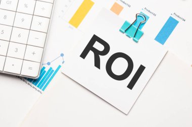 Roi metin konsepti. Hesap makinesi, grafik, rapor ve metin bütçesi 2021 ile ofis çalışma masası çok renkli arkaplan üzerine küçük bir kağıt parçası.