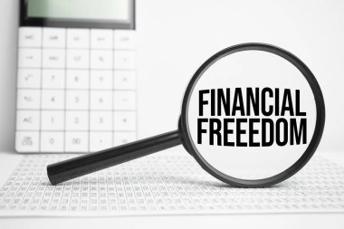 Hesap makinesi ile beyaz tablo üzerinde FINANCIAL FREEEDOM metin büyüteç