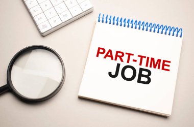 İş ve finans kavramı. Masanın üzerinde bir büyüteç, bir hesap makinesi ve üzerinde yarı zamanlı iş yazan bir defter var.