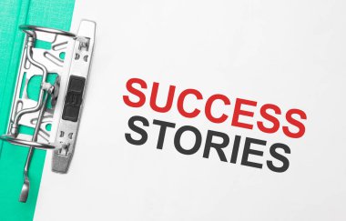 İş ve finans kavramı. Masanın üzerinde bir defter, bir kalem, belgeler ve üzerinde başarı hikayeleri yazan bir klasör var.