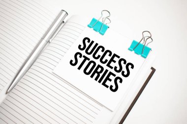 Beyaz gelecekteki hesap makinesi, kağıt çarşaf, pembe ataç ve gümüş renkli kalem. Metin başarı hikayeleri