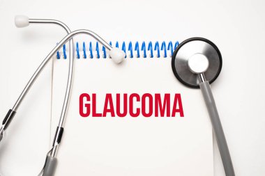 Üzerinde glokom yazan beyaz not defteri ve mavi arka planda steteskop. Tıbbi konsept