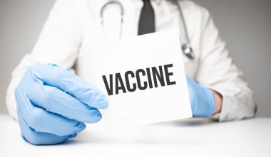 Doktor elinde bir kart tutuyor. Yazılı VACCINE, tıbbi konsept.