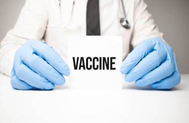 Doktor elinde bir kart tutuyor. Yazılı VACCINE, tıbbi konsept.