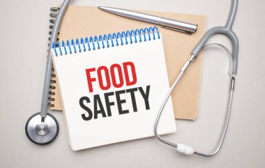 Üzerinde yiyecek güvenliği ve mavi arka planda steteskop yazan beyaz bir not defteri. Tıbbi konsept