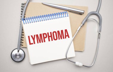 Üzerinde lenfoma yazan beyaz not defteri ve mavi arka planda steteskop. Tıbbi konsept