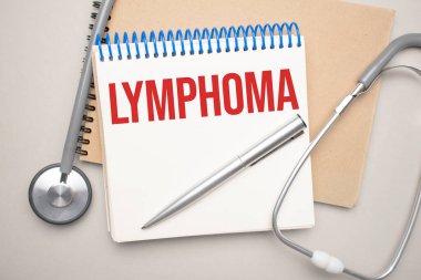 Üzerinde lenfoma yazan beyaz not defteri ve mavi arka planda steteskop. Tıbbi konsept