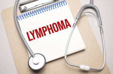 Üzerinde lenfoma yazan beyaz not defteri ve mavi arka planda steteskop. Tıbbi konsept