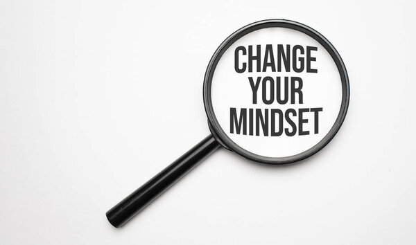 Finance and economics concept. Magnifier on a white background, inside the text is written - CHANGE YOUR MINDSET