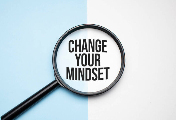 Finance and economics concept. Magnifier on a white background, inside the text is written - CHANGE YOUR MINDSET