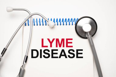 Üzerinde LYME hastalığı yazan beyaz not defteri ve mavi arka planda steteskop. Tıbbi konsept