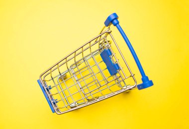 Sarı arka plandaki alışveriş arabasının fotokopi alanı ile yakın plan görüntüsü.