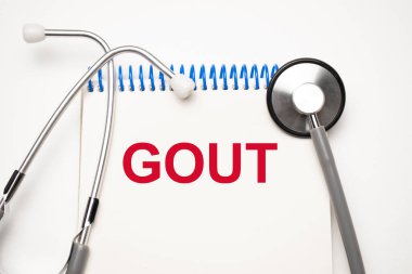 Mavi arka planda steteskop ve haplarla Gout mesajı olan kağıt