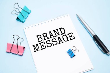 Yazılı beyaz not defteri BRAND MESAGE ve mavi arkaplan ofis araçları