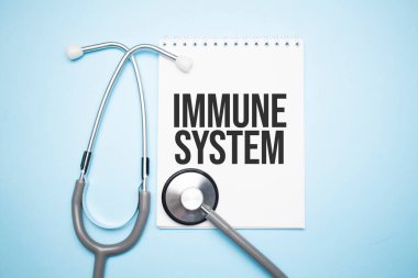 Stetoskop ve haplarla mavi zemin üzerinde metin bağışıklık sistemine sahip kağıt